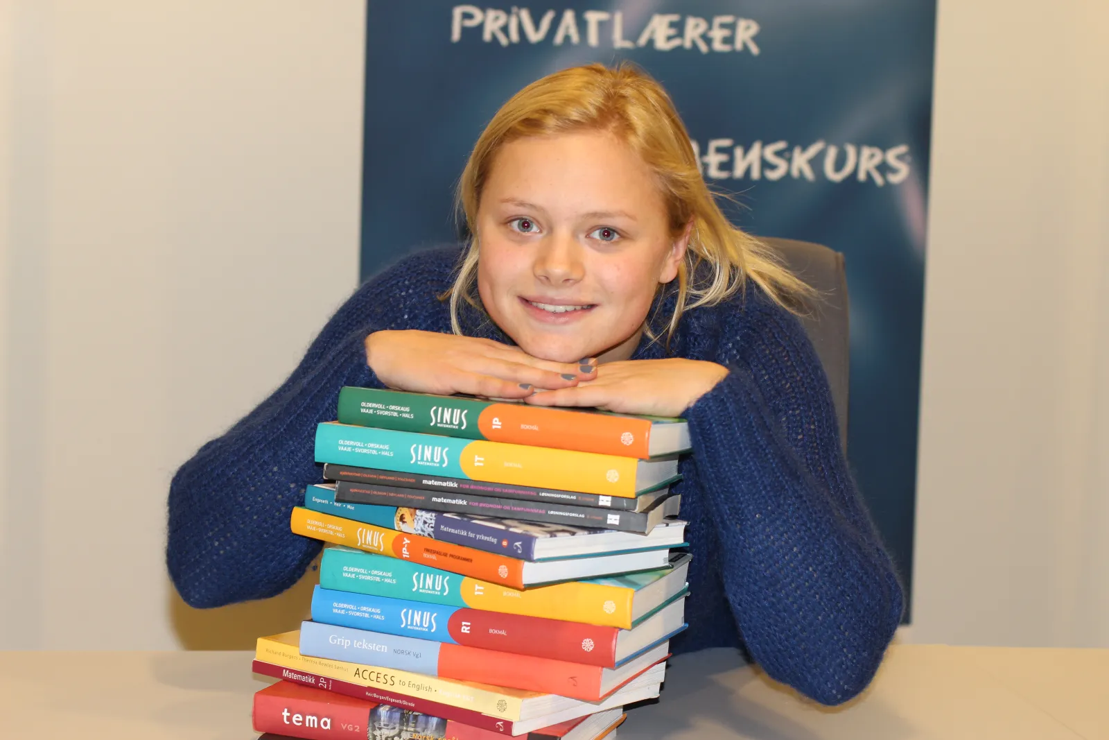 Smilende elev lener seg på en stabel med bøker